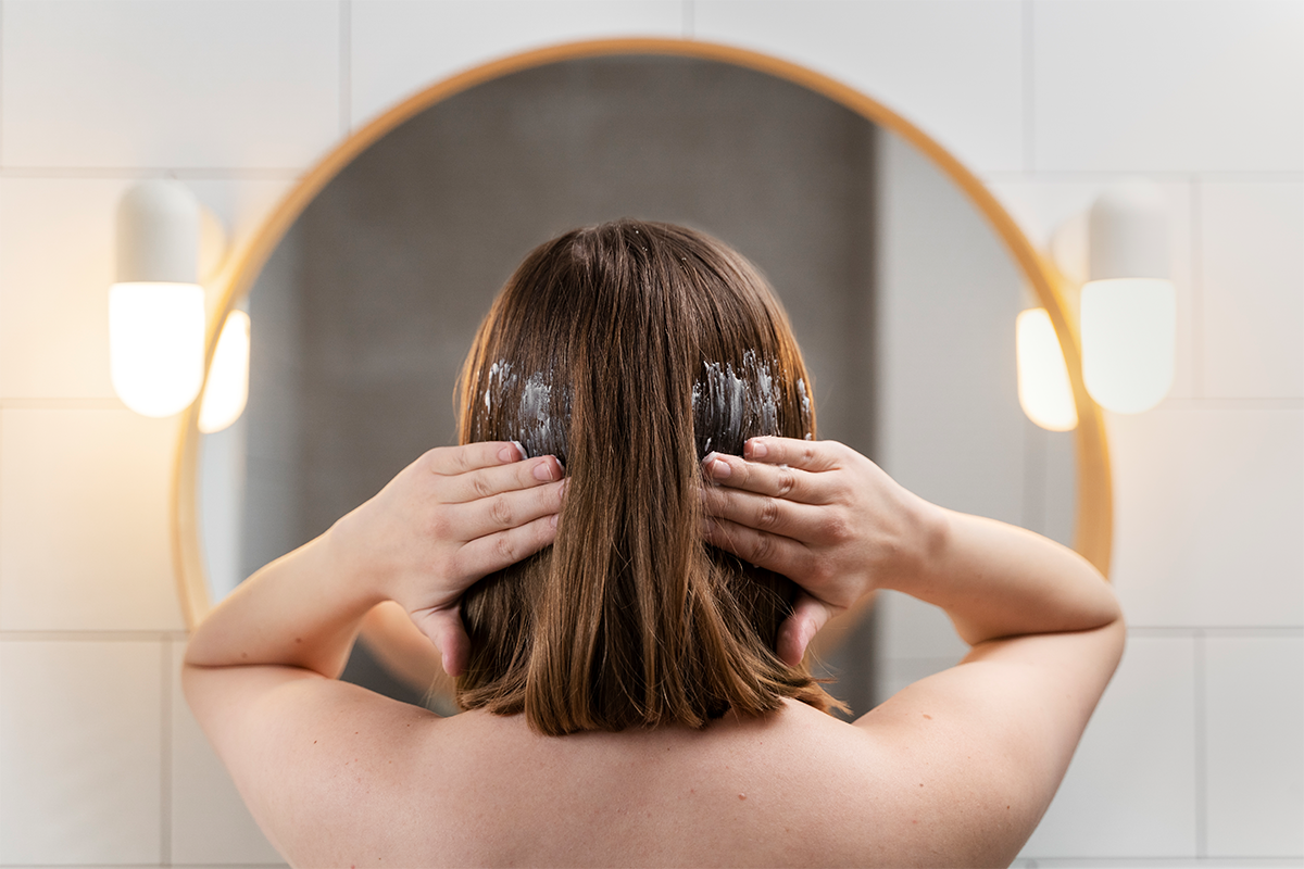Back View of a lady applying conditioner to her hair