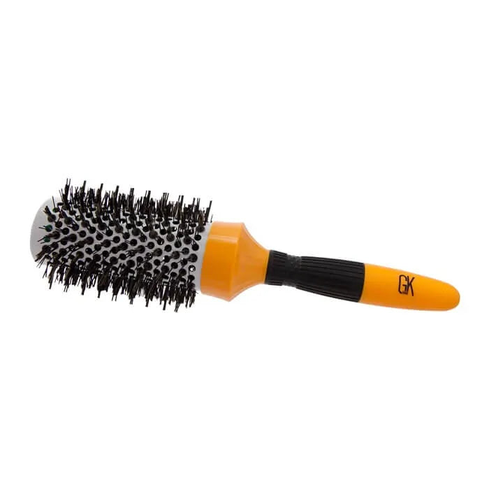 Extra Round Hair Brush lying on its side, vented barrel of black bristles with an orange and black handle marked GK